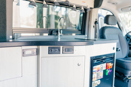 Explore this RV rental's equipped kitchen: sink, induction point, fridge, and Xantrex power panel. Comfort on the road.
