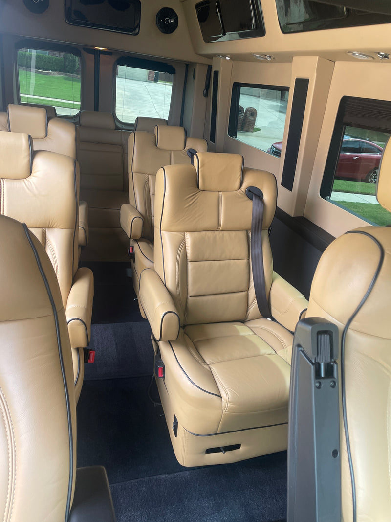 Luxury RV rental interior with rows of comfortable tan leather captain's chairs, ideal for group travel. — photo 2