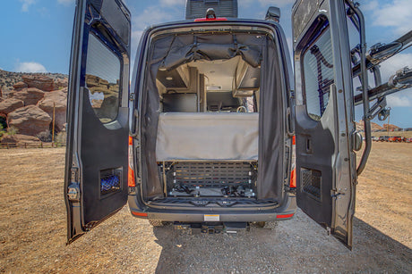 Explore the outdoors with this RV rental! Rear of an open camper van showcasing its interior, bed, storage, and bike rack.
