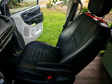 RV rental interior: Black quilted leather seat & open door revealing green grass.