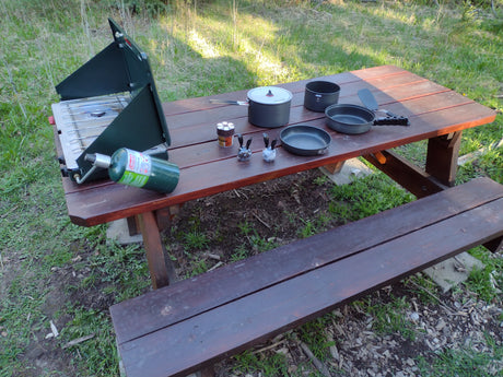 Enjoying outdoor cooking with an RV rental! Picnic table holds camping stove, propane, cookware, and spices.
