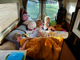 Kids enjoying an RV rental adventure. Three children cozy inside a camper van, perfect for family travel and camping.