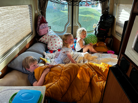 Kids enjoying an RV rental adventure. Three children cozy inside a camper van, perfect for family travel and camping.