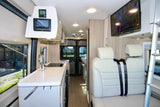 View inside a sleek rv rental: a compact kitchen, electronic controls, comfortable seating, and wall-mounted TV.