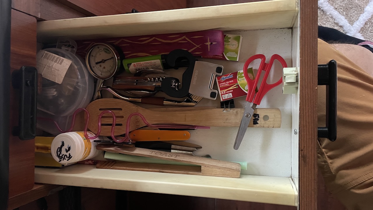 Cluttered RV rental kitchen drawer: utensils, matches, scissors, and tools. A versatile storage solution for compact living.