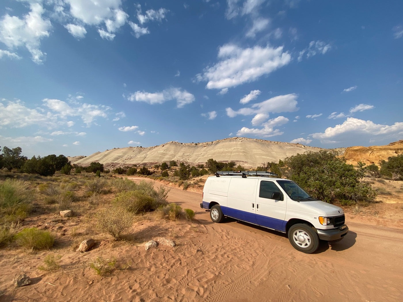 Adventure-ready RV rental van parked on a scenic desert dirt road, with majestic hills under a blue sky. — photo 17