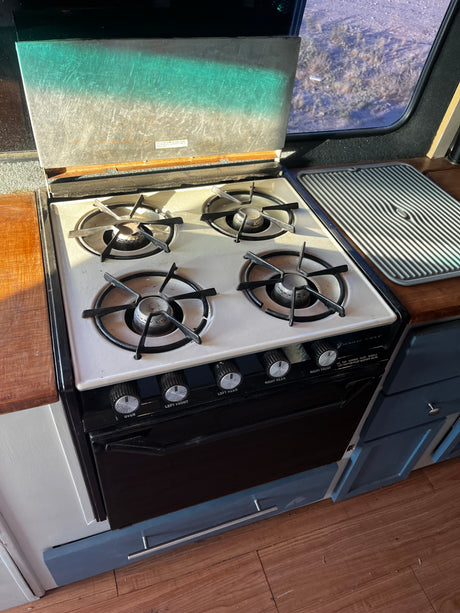This RV rental features a vintage Magic Chef 4-burner gas stove with oven, ready for cooking on the road.
