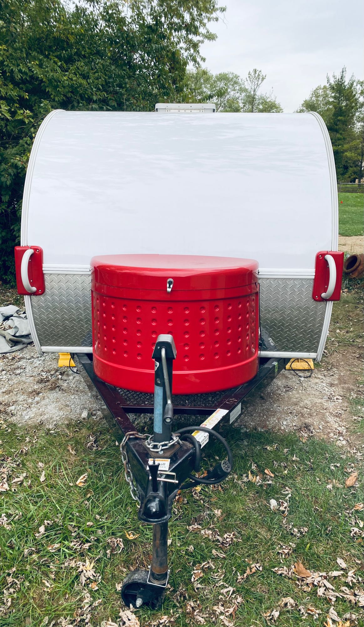White teardrop RV rental featuring a prominent red front storage box, ideal for camping adventures.