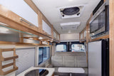 Bright rv rental interior: compact kitchen, microwave, fridge, comfortable seating, and overhead cabinets for travel.
