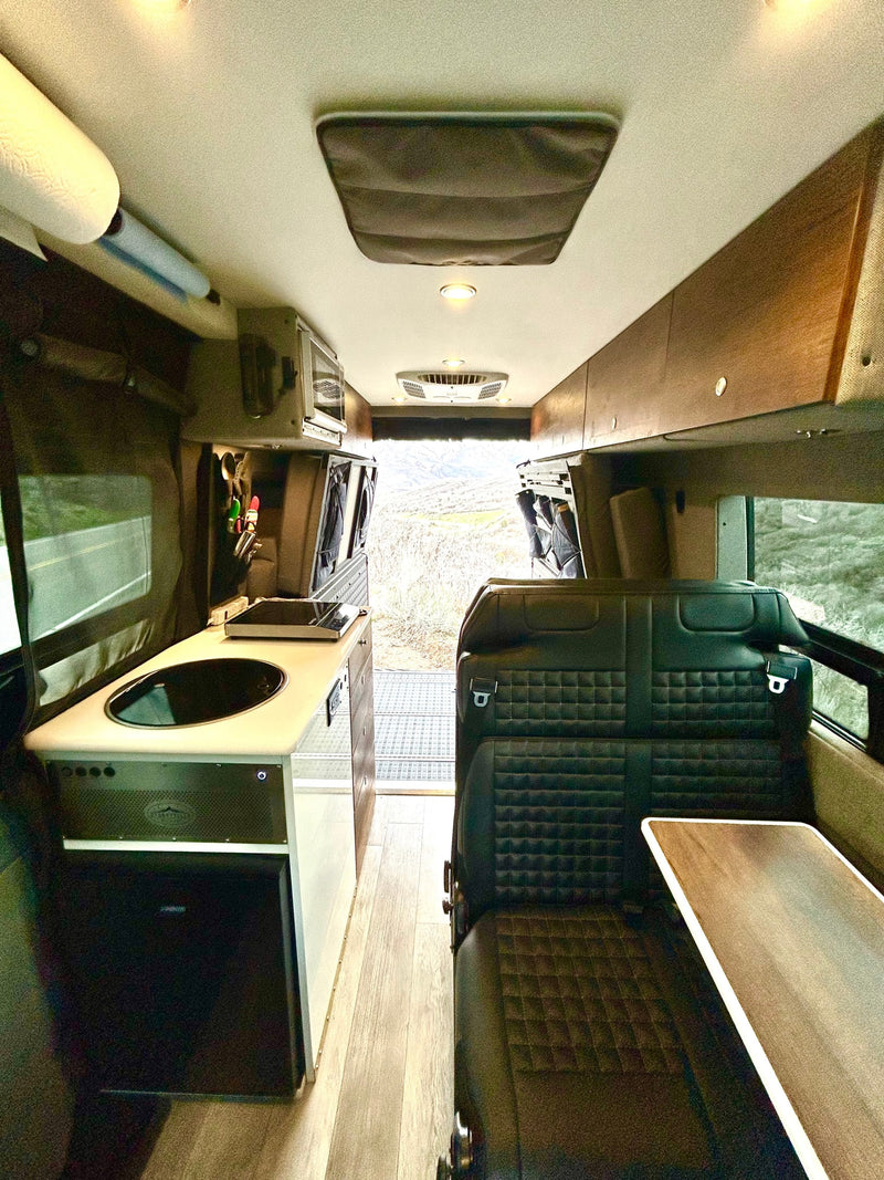 RV rental interior: A modern camper van with a compact kitchen, comfortable seating, and stunning mountain views out the back. — photo 16