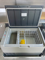 An open portable refrigerator, often found in an RV rental, showing its dual compartments, wire basket, and controls.