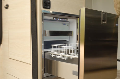 RV rental: Isotherm pull-out refrigerator with wire basket and awning controls, showcasing efficient camper storage.