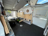 RV rental's versatile interior: pop-up roof, convertible bed with under-storage, textured floor, and open rear. Ready for trips.