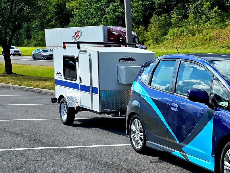 Blue Honda Fit towing a compact Runaway teardrop RV rental — photo 1