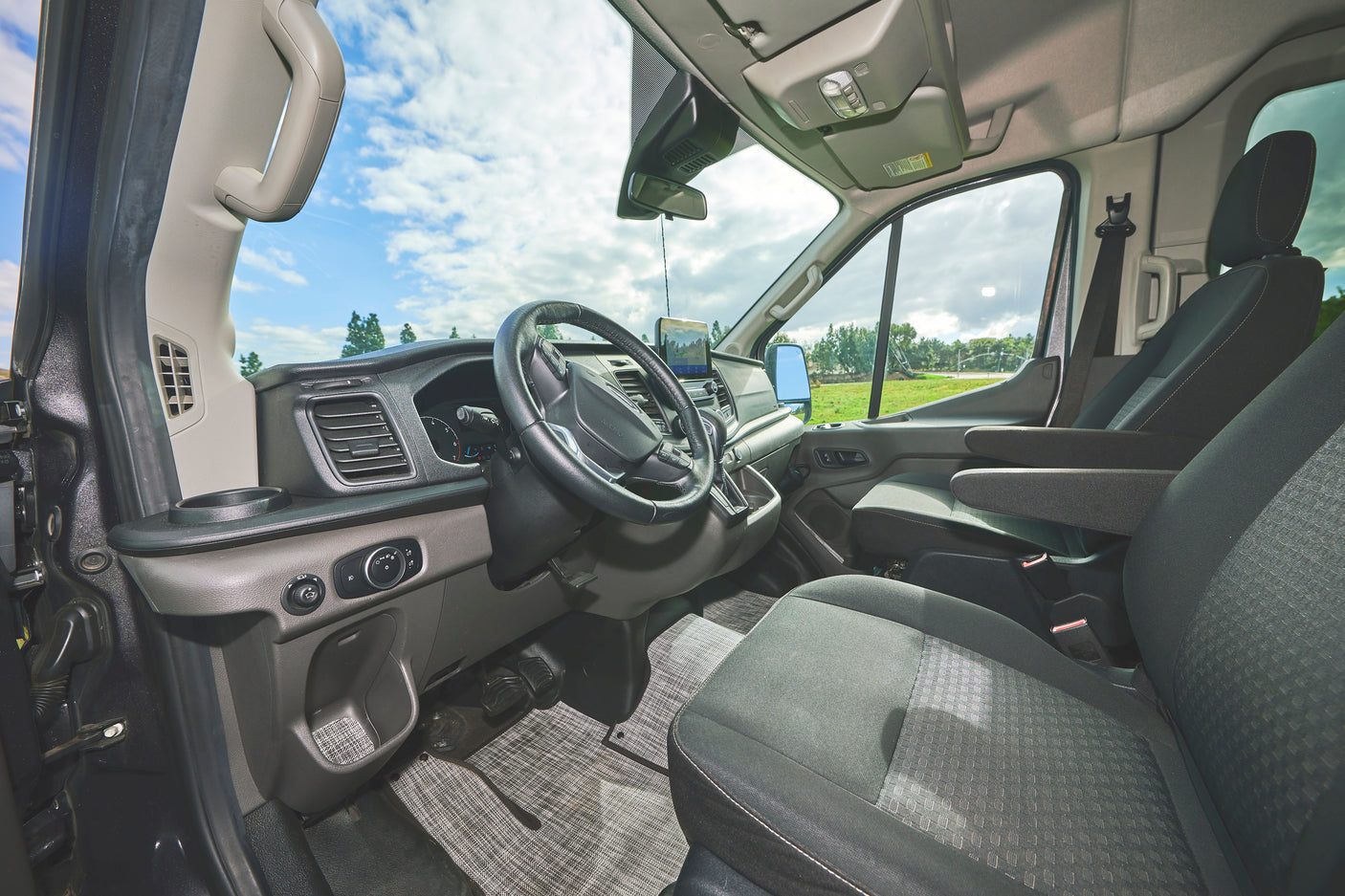 Inside this RV rental: a detailed view of the front cabin, showing the dashboard, steering wheel, and seats.