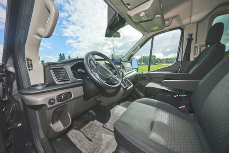 Inside this RV rental: a detailed view of the front cabin, showing the dashboard, steering wheel, and seats.