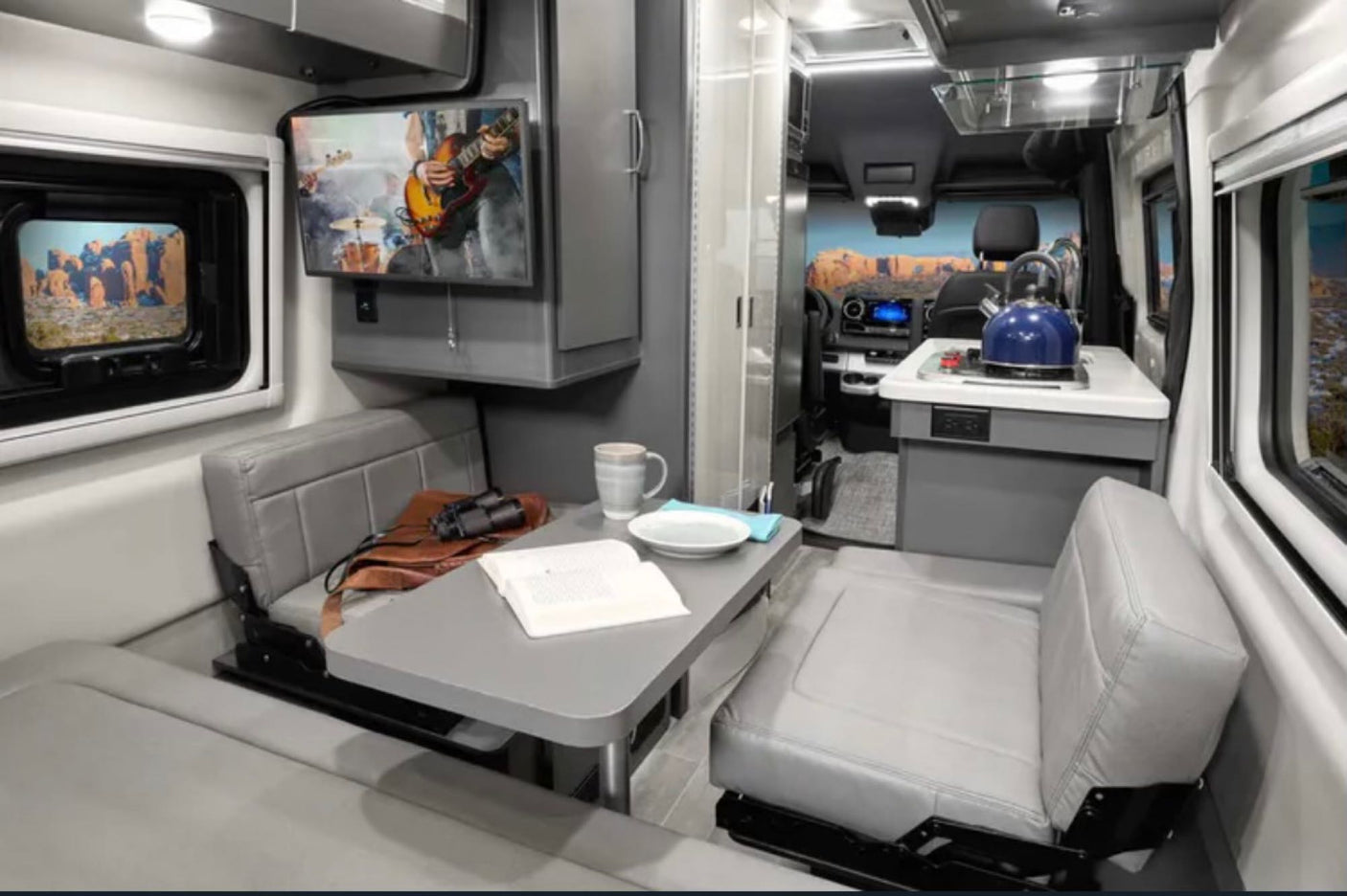 RV rental: The cozy, modern interior of a camper van with dining, kitchen, and wall-mounted TV.