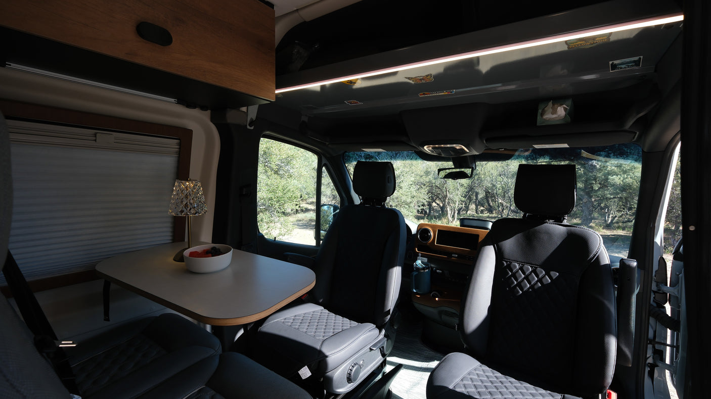 Experience comfort in this rv rental's interior, featuring swivel seats, a dining table with fruit, and nature views.