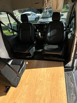 RV rental van interior: black front seats, dash, light wood floor extending to rear seating.