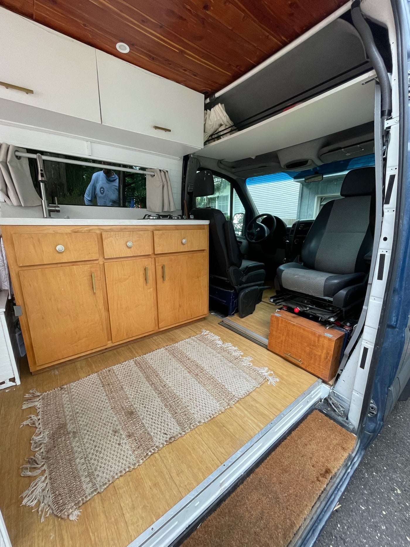 Cozy RV rental interior with a functional kitchen, wooden cabinets, overhead storage, and swivel front seats. — photo 4