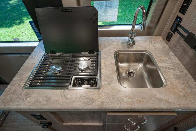 Compact RV rental kitchenette featuring a built-in two-burner stove with cover and a stainless steel sink, perfect for travel cooking. — photo 15