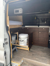 Inside this RV rental van, a full conversion with a bed, kitchenette, microwave, and clever pull-out toilet system.