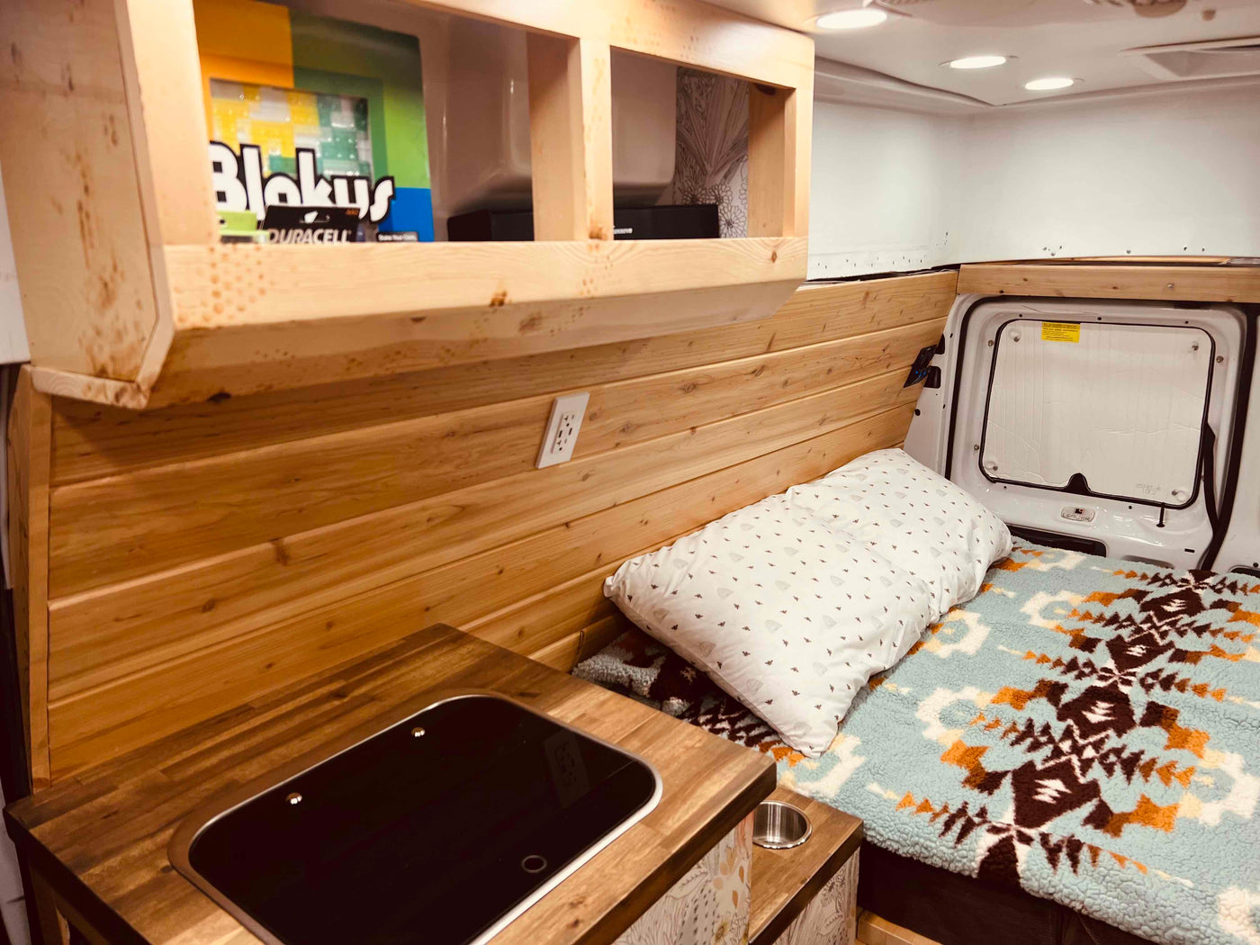  and a WFCO power panel with visible circuit breakers.|RV rental: View inside a camper van's converted living space with two cushioned benches — photo 2
