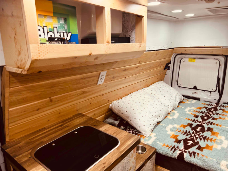  and a WFCO power panel with visible circuit breakers.|RV rental: View inside a camper van's converted living space with two cushioned benches — photo 2