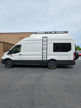 White Ford Transit RV rental camper van, featuring a roof rack, side ladder, and spare tire on the back.