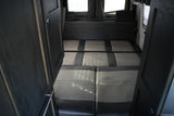 RV rental: Interior with open dark wood doors framing a convertible gray & dark cushion seating/bed & back window.
