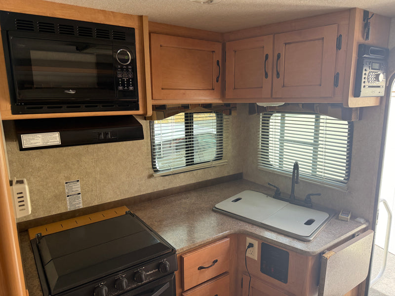 This rv rental kitchen features a High Pointe microwave, Suburban stove, sink, and wood cabinets. Everything needed for your trip! — photo 10