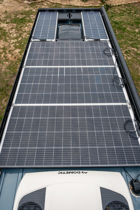 High angle shot of an RV rental roof with extensive solar panels and a Dometic AC unit for off-grid comfort.