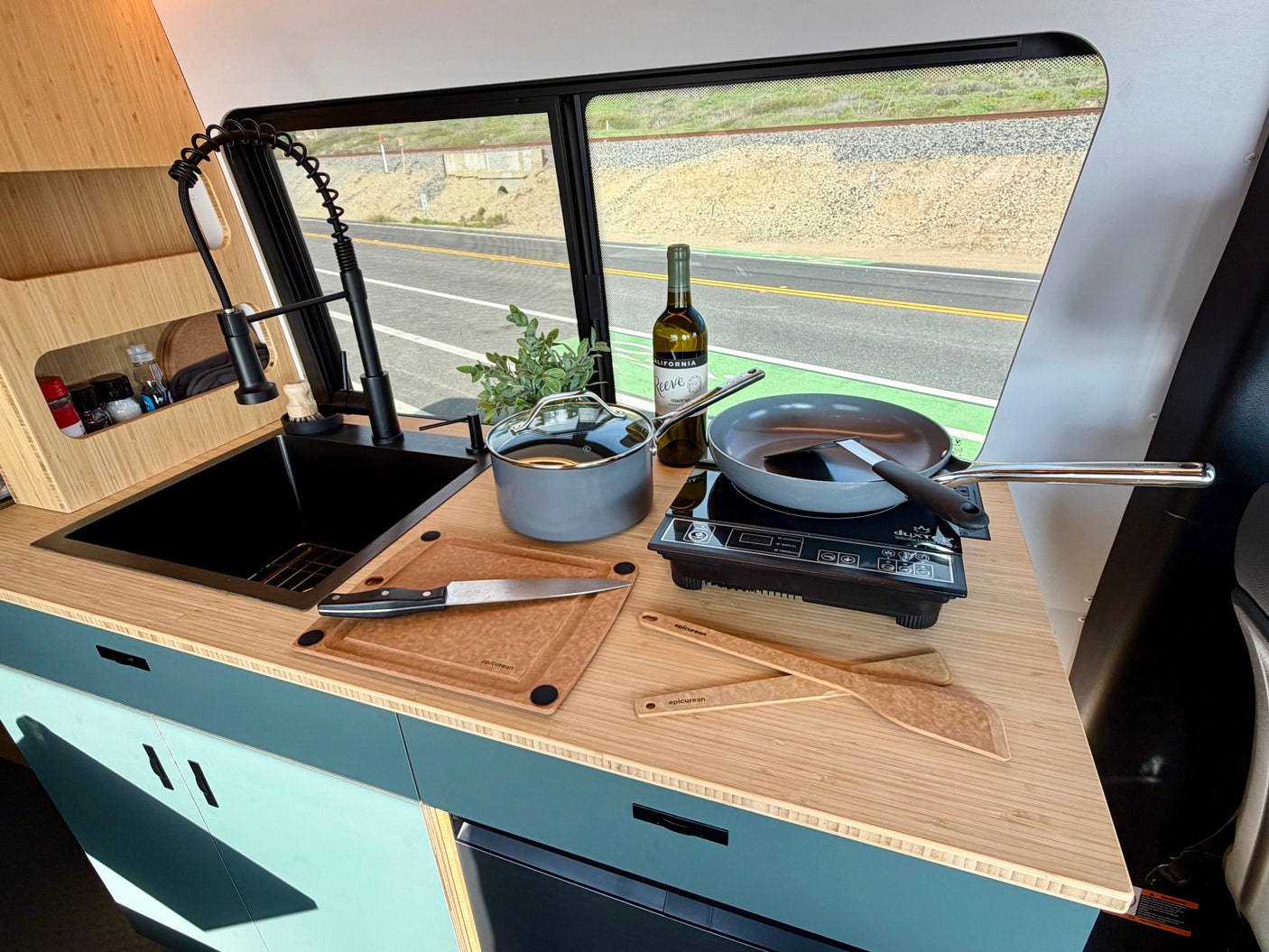 Well-equipped RV rental kitchen featuring a sink, induction cooktop, and cookware, ideal for cooking while traveling.