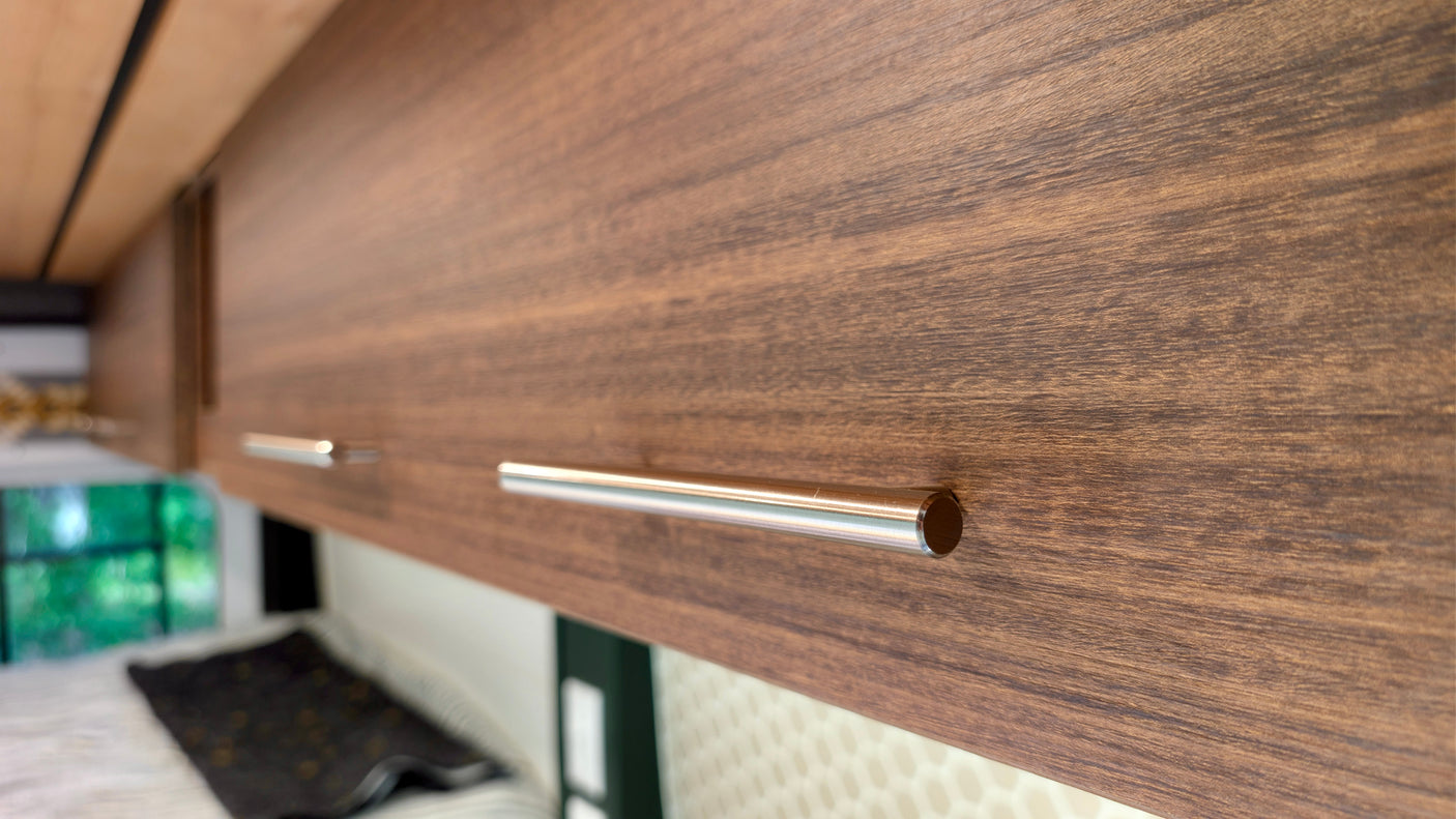 Sleek wooden overhead cabinets with modern metal handles inside an RV rental. Provides essential storage for travelers.