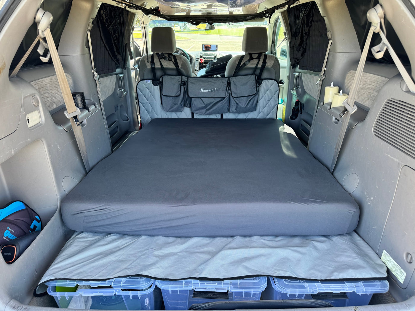 RV rental alternative: Minivan interior transformed for car camping. Features a comfortable bed, under-bed storage, and privacy curtains. — photo 7