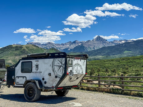 Mission Overland trailer for RV rental, parked amidst majestic Colorado mountains under a clear sky.