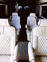 Spacious luxury RV rental interior with four plush, cream quilted leather seats facing each other. Perfect for travel comfort.