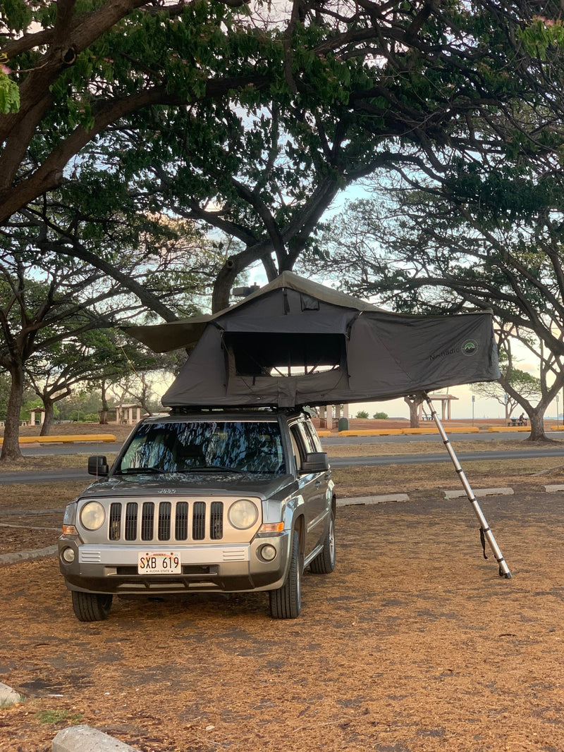 An RV rental Jeep with a deployed Nomadic rooftop tent, ready for camping in a scenic Hawaii park, offers comfortable outdoor adventure. — photo 5