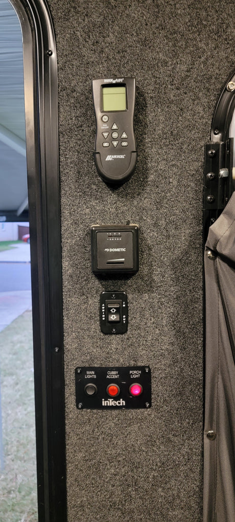 RV rental control panel featuring climate, awning, and lighting switches for a comfortable journey. Porch & accent lights are on.