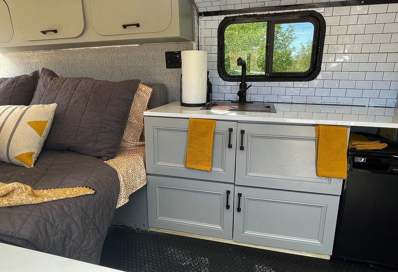 Stylish RV rental interior with a cozy bed, modern kitchenette featuring white subway tiles, and grey cabinets. — photo 3