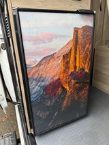 This RV rental's custom fridge door displays a stunning mountain landscape mural, complementing the camper's interior.