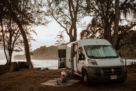 RV rental camper van camped by the ocean, with chairs and cooler set up for a relaxing beachside escape.