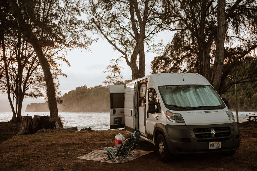 RV rental camper van camped by the ocean, with chairs and cooler set up for a relaxing beachside escape.