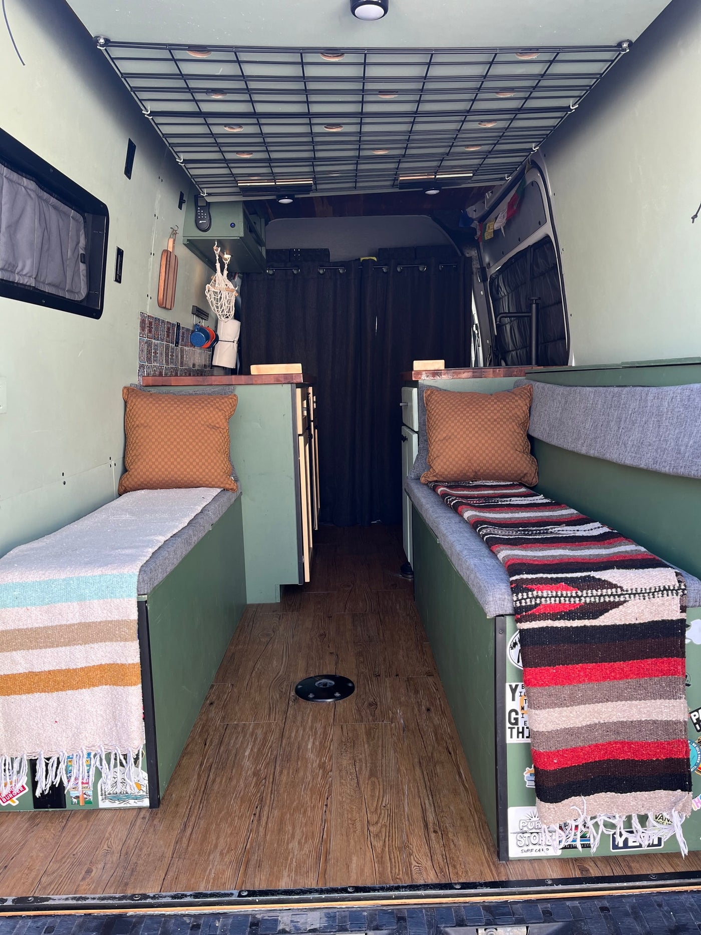  with cozy benches and an upper bed.|Inside a modern RV rental: comfy green & gray bench with storage — photo 4