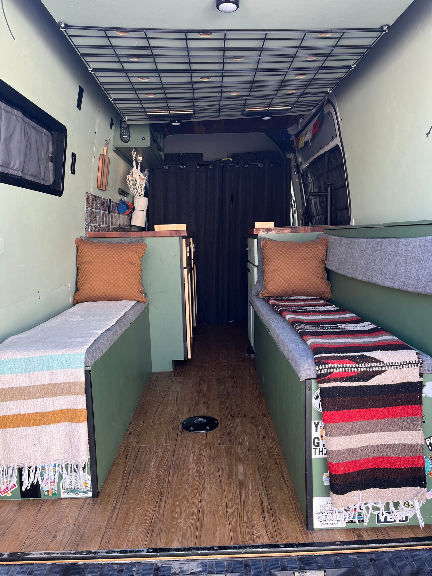 Custom RV rental interior with comfy benches, wooden floor, and grid storage. Ideal for van life adventures.