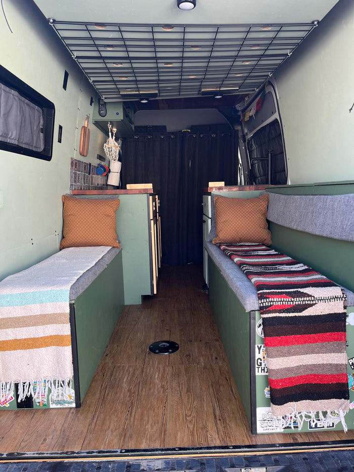 Custom RV rental interior with comfy benches, wooden floor, and grid storage. Ideal for van life adventures.