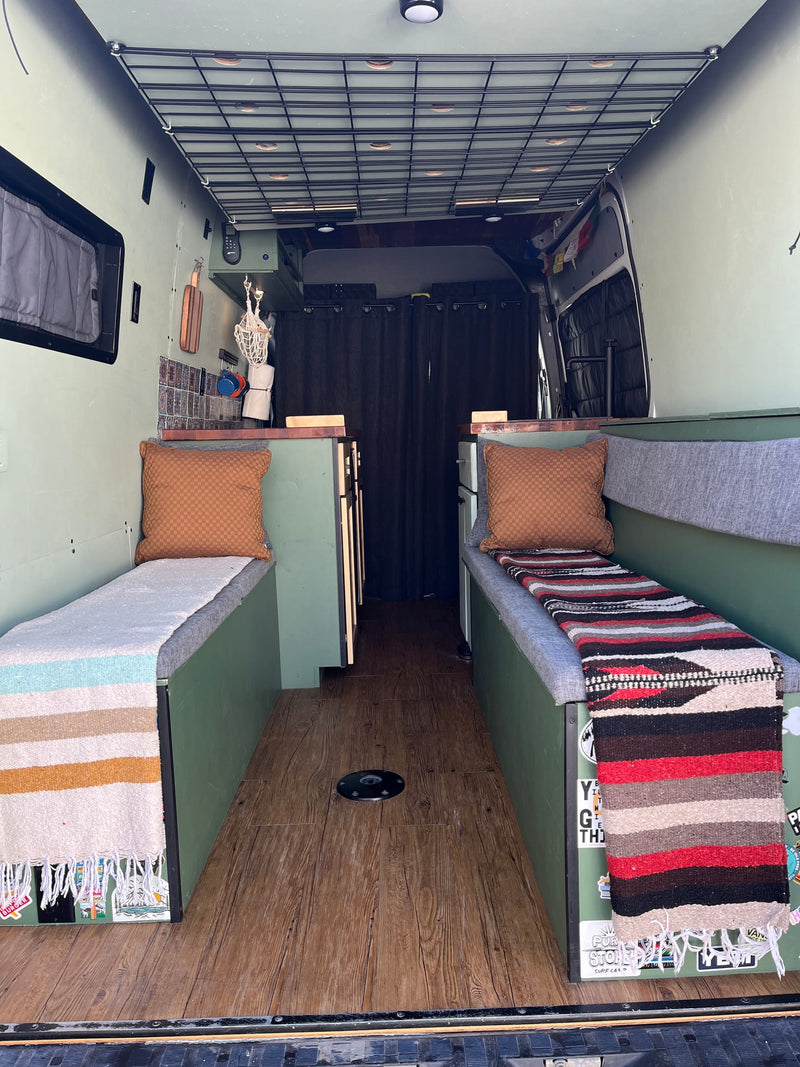  with cozy benches and an upper bed.|Inside a modern RV rental: comfy green & gray bench with storage — photo 4