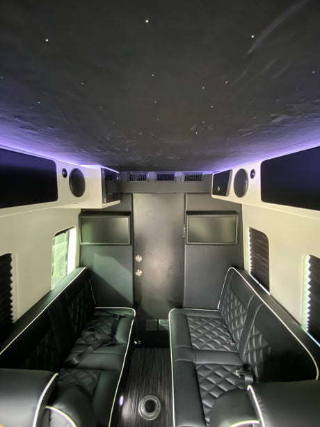 Plush interior of an **rv rental**: black quilted leather seats, star ceiling, screens & audio for luxury travel.