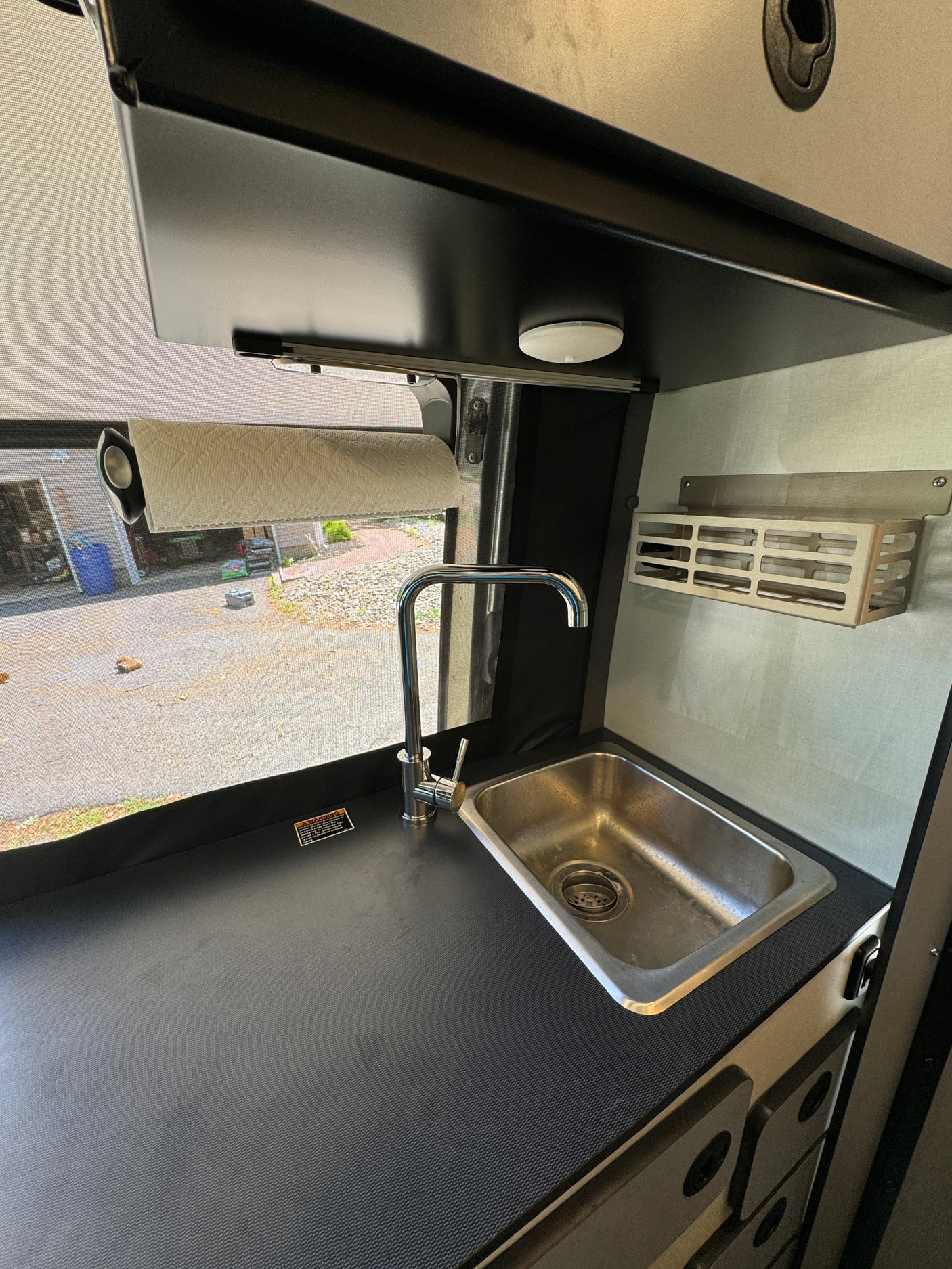 Compact RV rental kitchen with a sleek stainless steel sink, modern chrome faucet, and convenient paper towel holder.