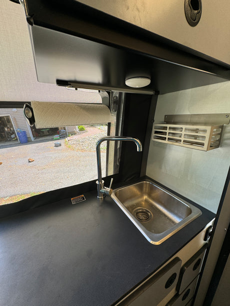 Compact RV rental kitchen with a sleek stainless steel sink, modern chrome faucet, and convenient paper towel holder.